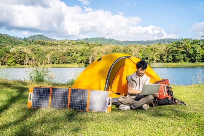 Solar Panels next to a yellow tent with a man on a lap top