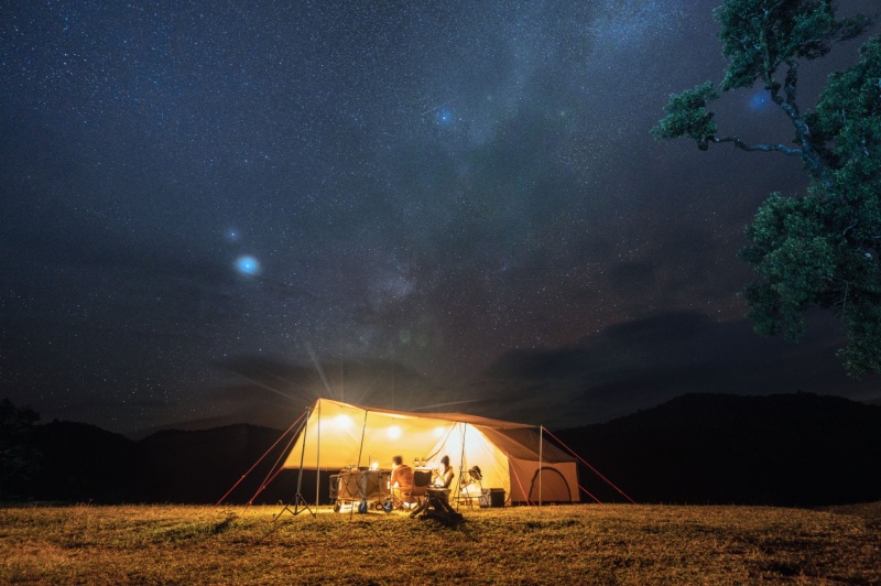 Couple tourist resting in yellow tent camping on hill with starry in the night sky at national park